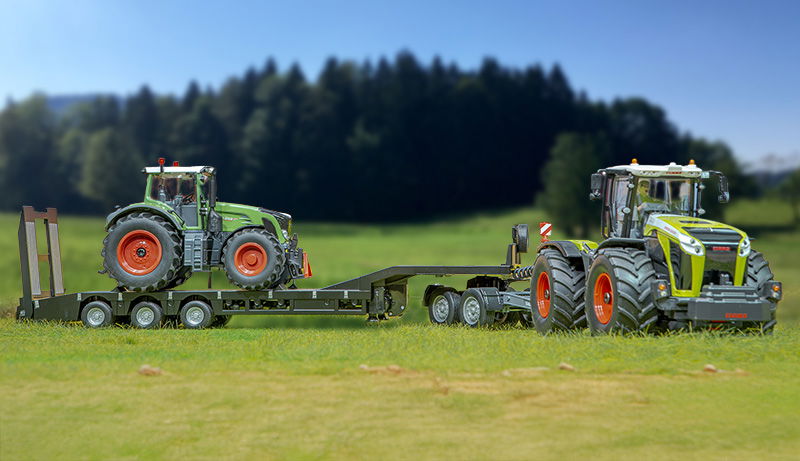 SIKUCONTROL Sommeraktion Kategoriebanner sikucontrol claas Xerion mit Tiefbettsattelauflieger . Fendt Traktor steht auf Anhänger. Fahrzeuge stehen auf Feld mit Wald im Hintergrund