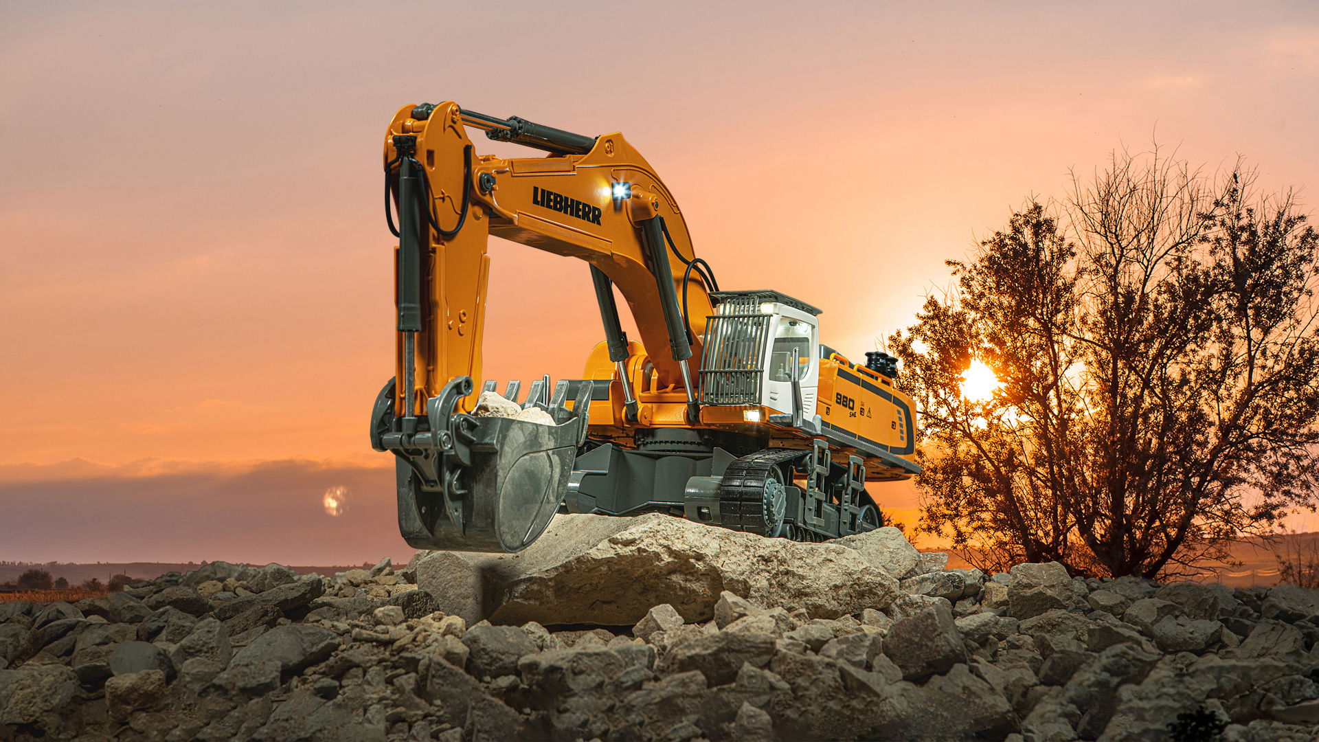 Ein SIKUCONTROL Liebherr Bagger steht auf einem Geröllhaufen. Im Hintergrund ist ein Sonnenuntergang  zu sehen