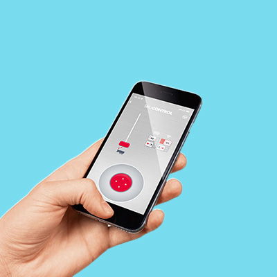 Eine Hand hält ein Handy , auf dem Display ist die SIKUCONTROL APP Steuerung zu sehen. Der Hintergrund ist blau