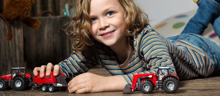 Kind, das mit rotem SIKU-Traktor spielt